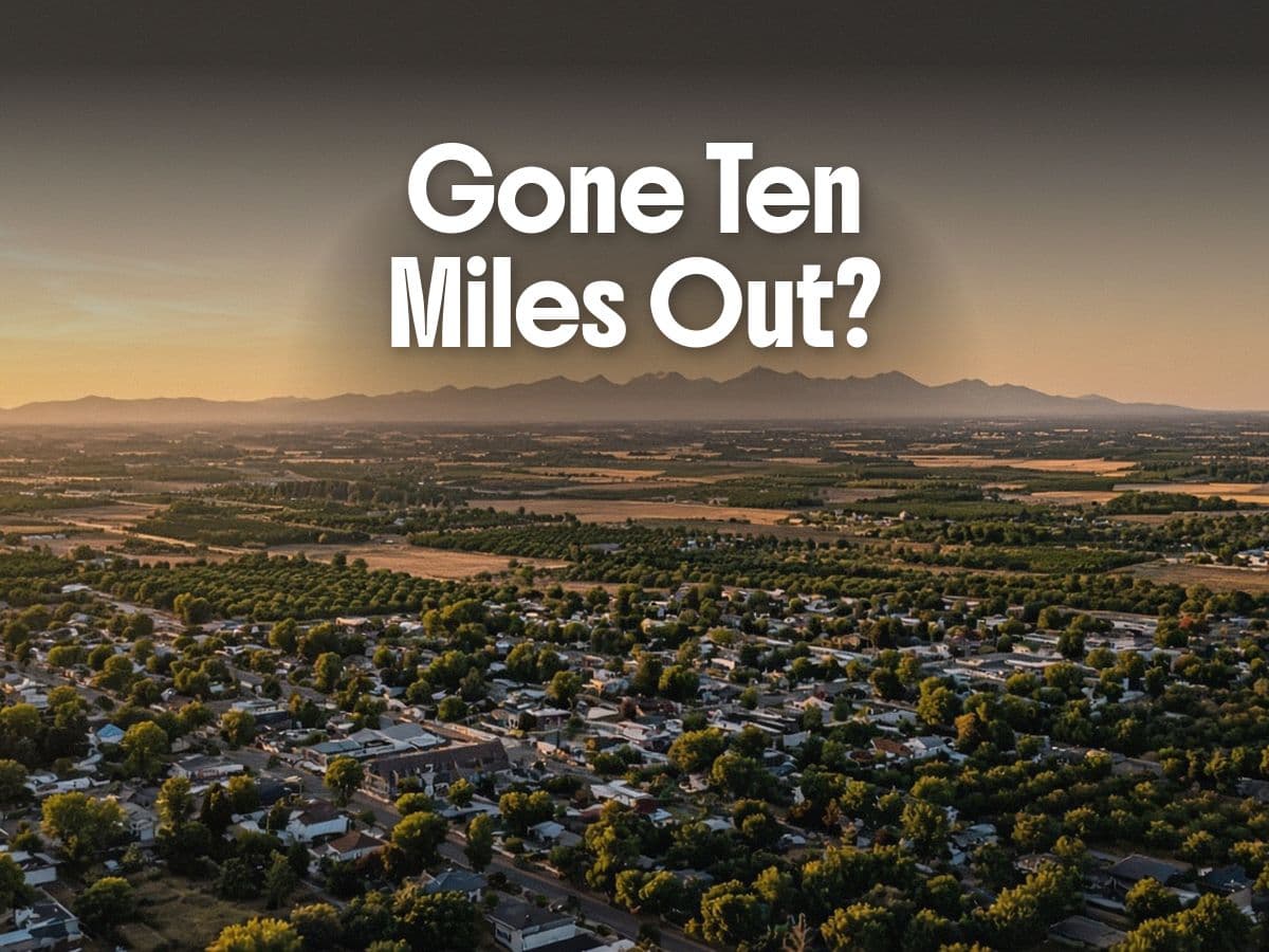 Aerial view of a tree-lined town, farmland, and mountains at sunset, under the words Gone Ten Miles Out?